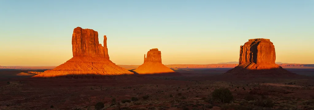 The Mittens and Merrick Butte glowing orange in the last light of sunset, Monument Valley