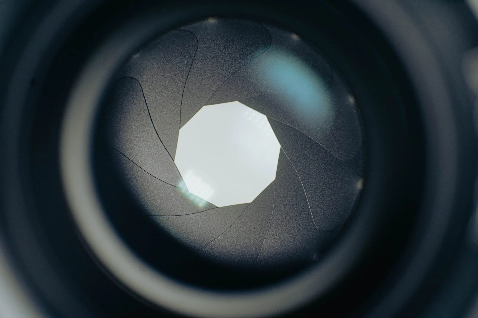 Aperture blades stopped down inside a camera lens, forming a rounded opening