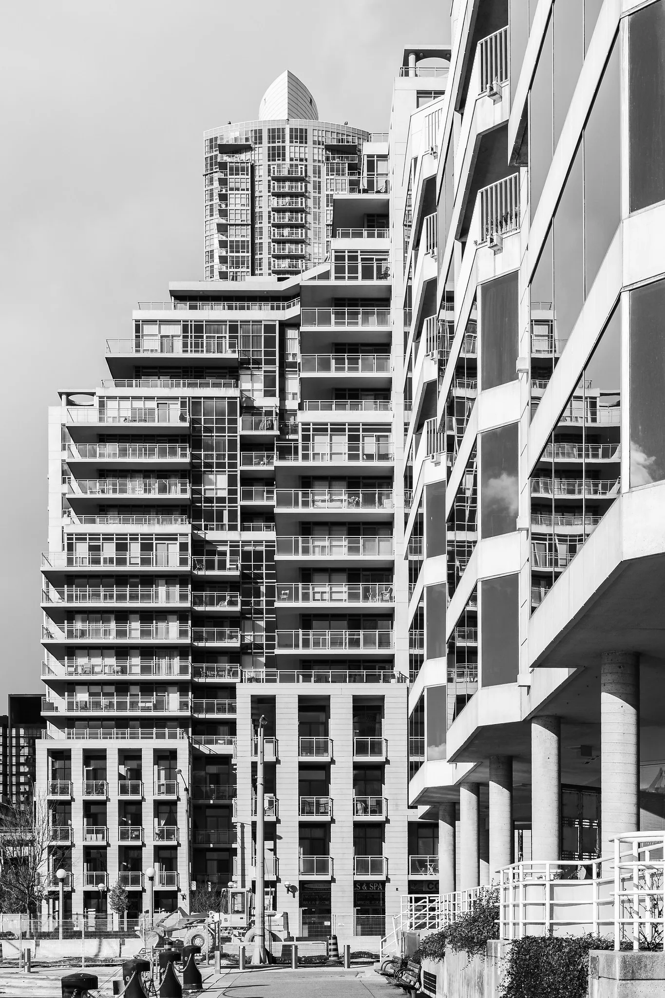 Black and white photograph of high-rise residential towers with repeating balconies against a plain pale sky