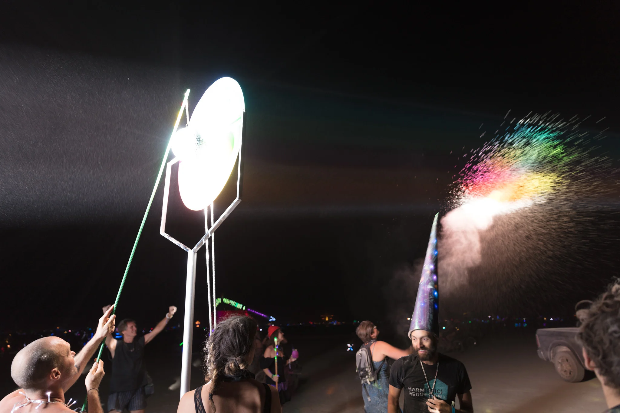 People gathered close around a small bright light source at night, brightness dropping off quickly just a few meters away
