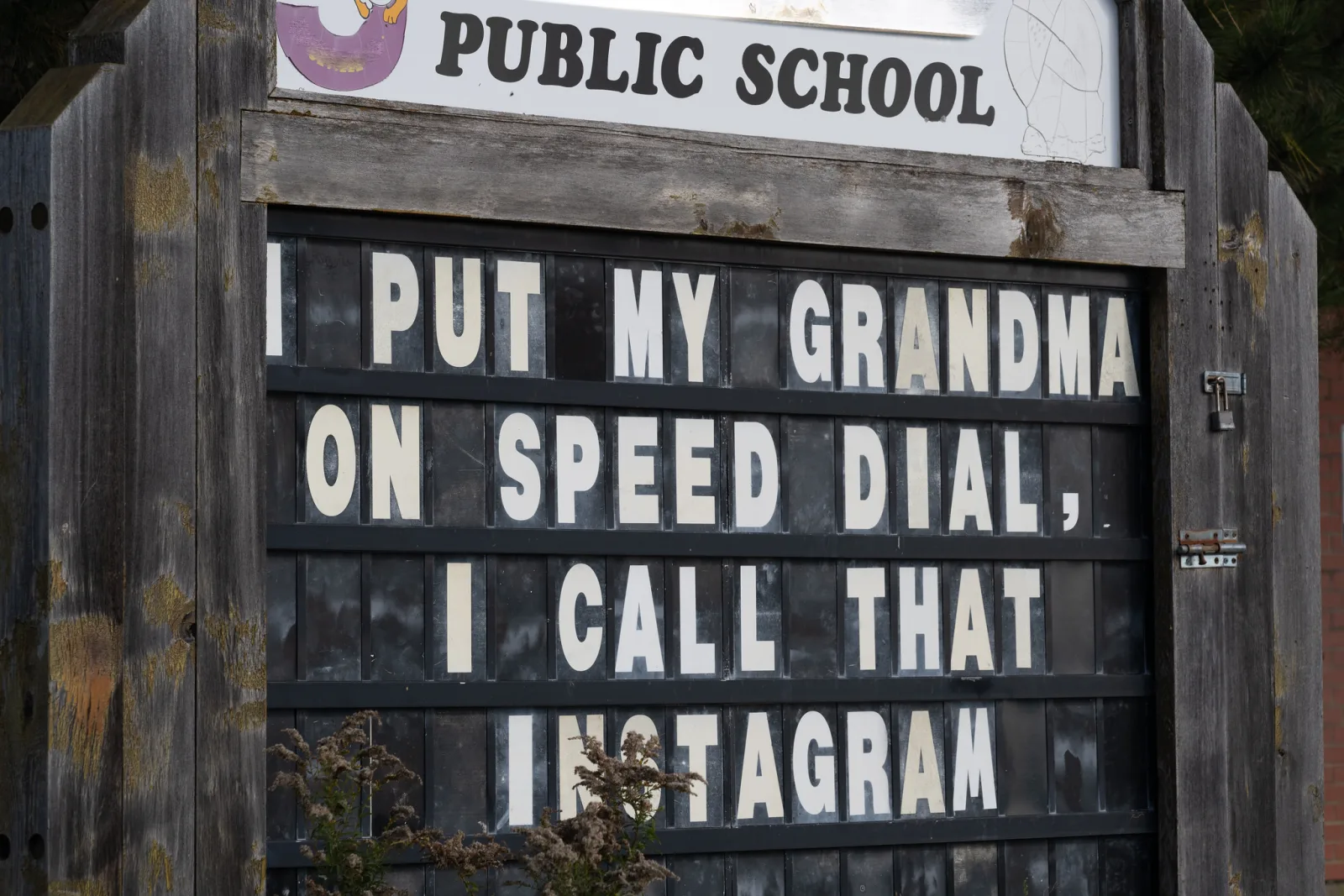 A letter board sign outside a public school with a joke about putting grandma on speed dial spelled out in white capital letters