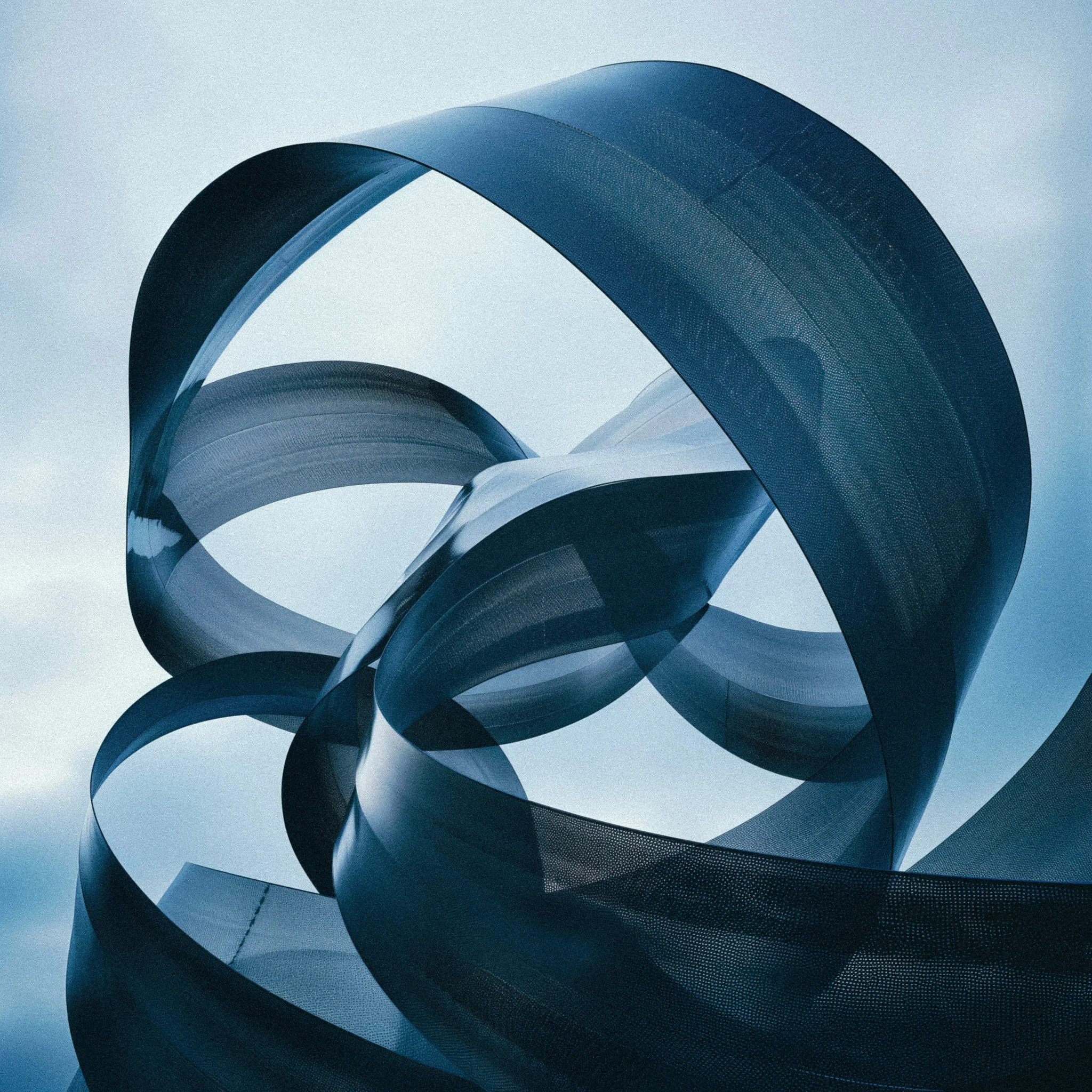 Large abstract steel ribbon sculpture with continuously flowing curved surfaces against a pale sky, photographed from below