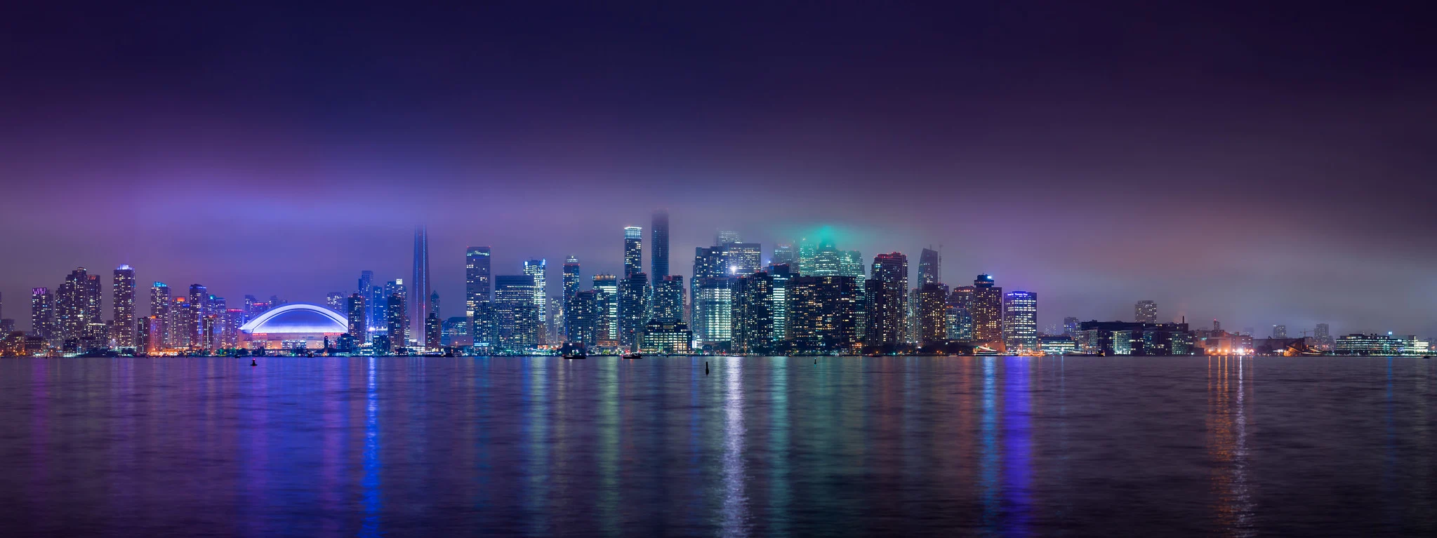 Toronto skyline reflected in the lake at night, tall buildings creating strong vertical lines