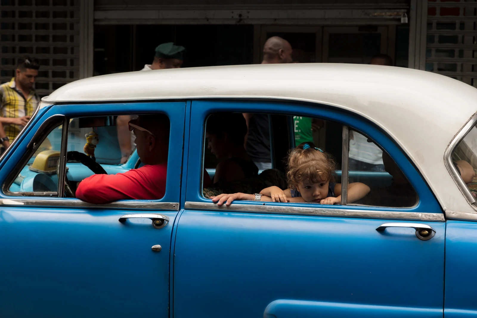 A girl looking out of a vintage car window in Havana