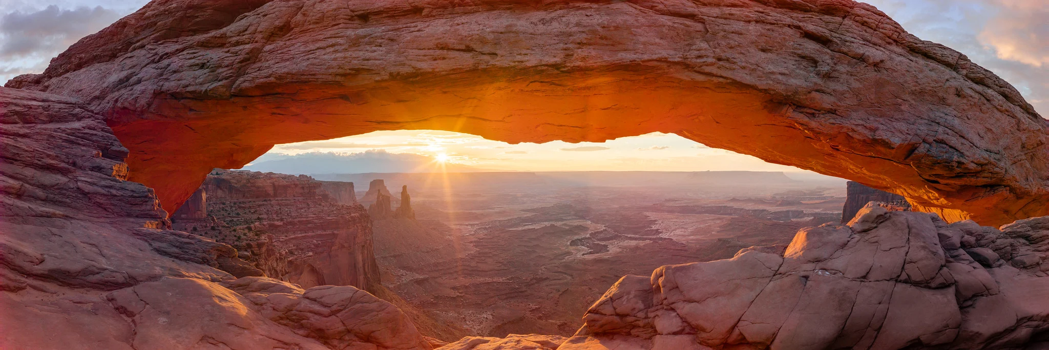 Sunrise seen through a natural rock arch, with detail preserved in both the bright sun and the shadowed rock.