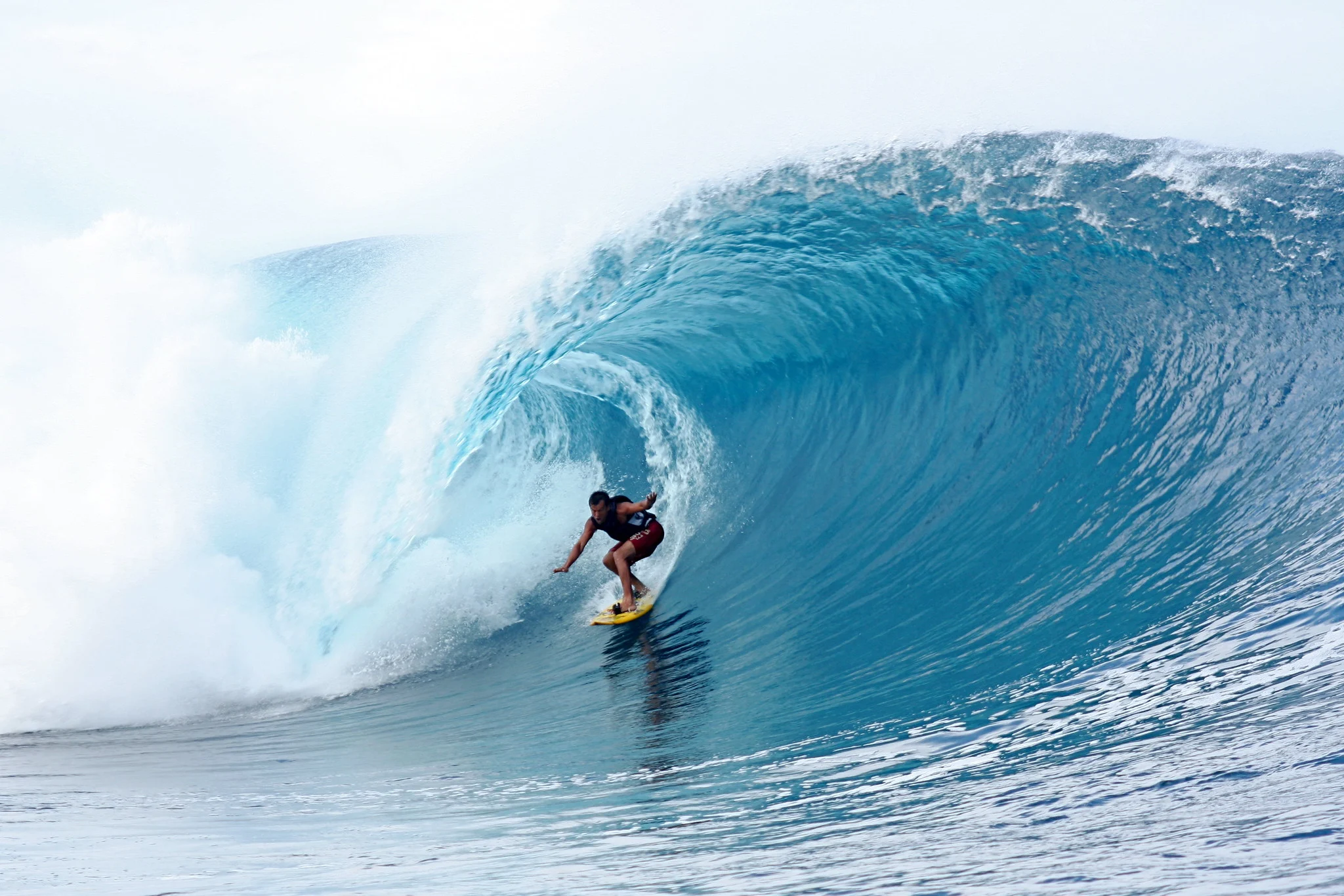 A surfer riding inside the curl of a large wave at Teahupoo, frozen sharp by a fast shutter speed.