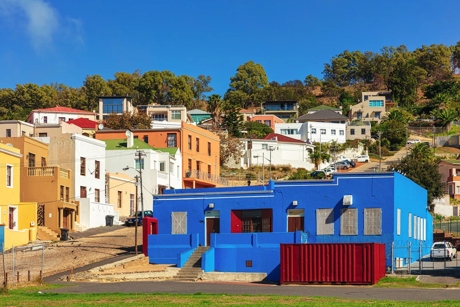 A bright blue painted building in front of a hillside of colorful houses, showing how a strong colored backdrop sets the mood of a scene