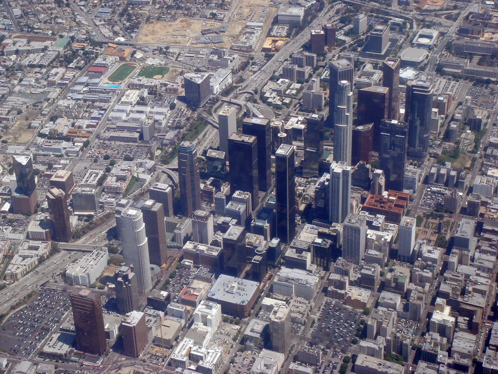 A dense cluster of downtown skyscrapers and the street grid around them, seen from high in the air.
