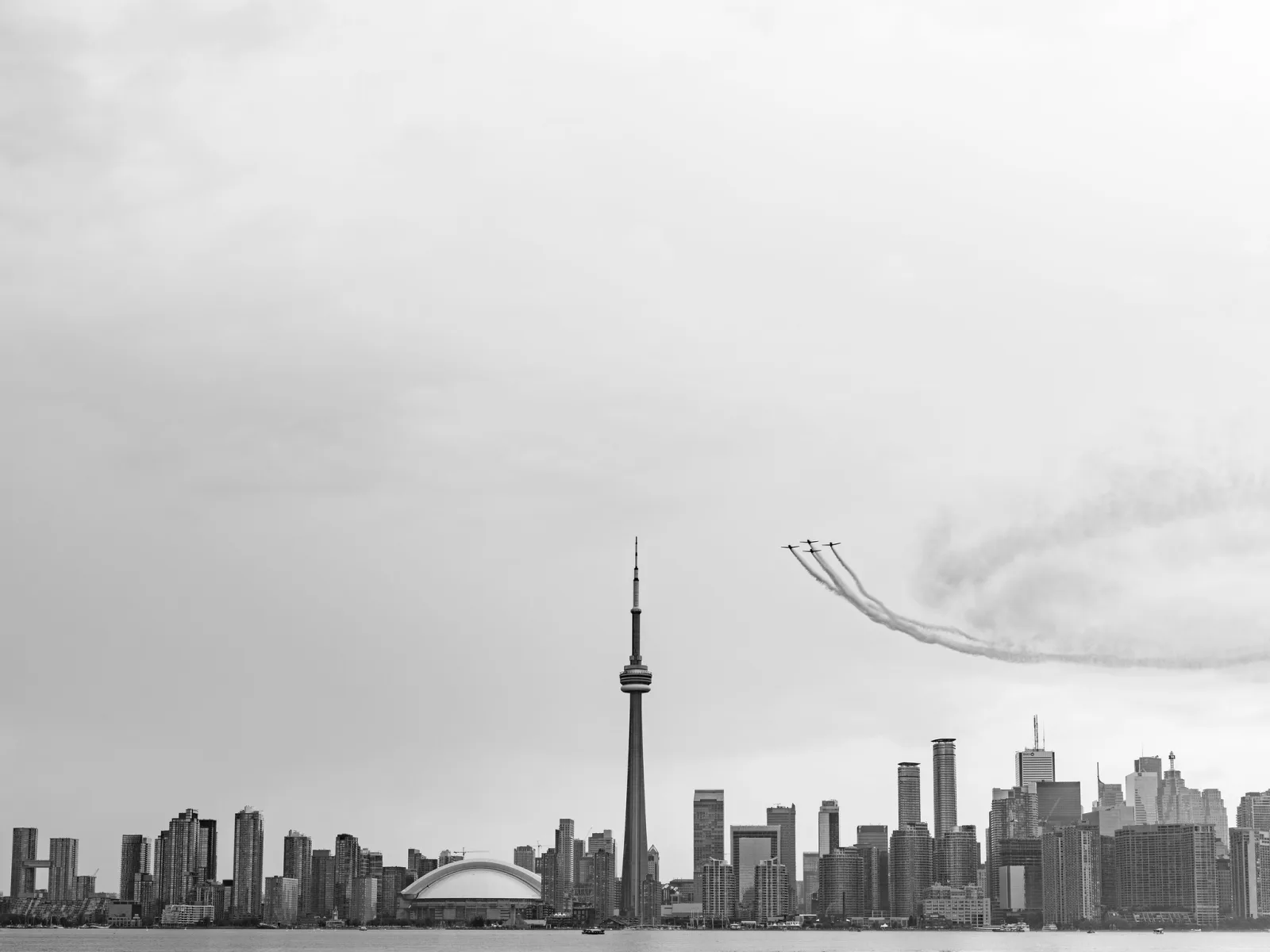 A formation of jets trails smoke above the Toronto skyline and the CN Tower.