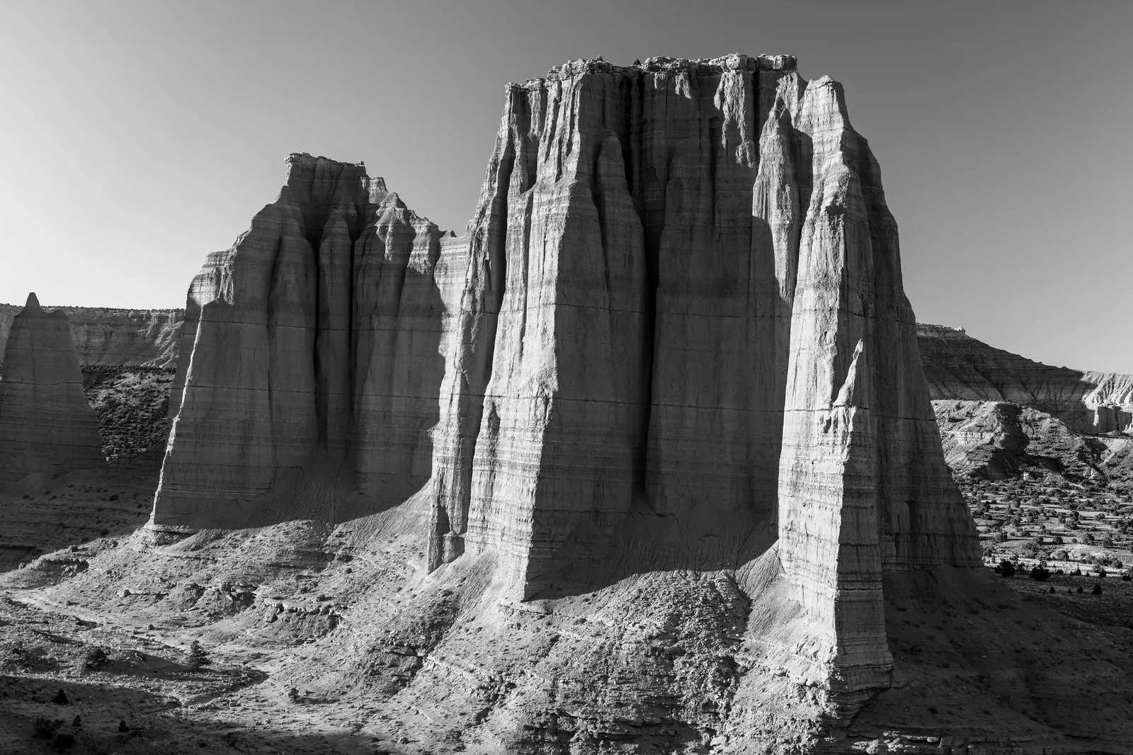 Black and white photo of a tall sandstone monolith in Cathedral Valley, with one side brightly lit and the other in deep shadow, showing a strong lighting ratio
