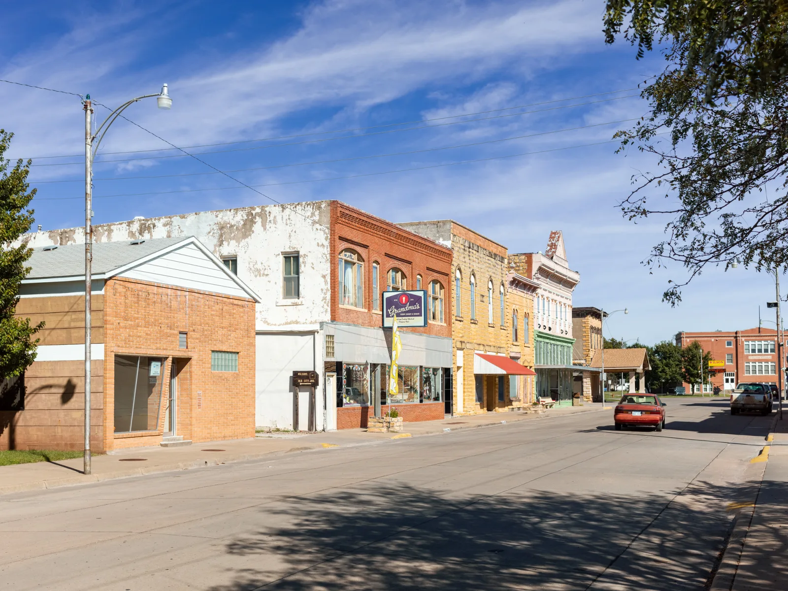 A quiet main street lined with low brick storefronts under a blue sky with thin cloud.